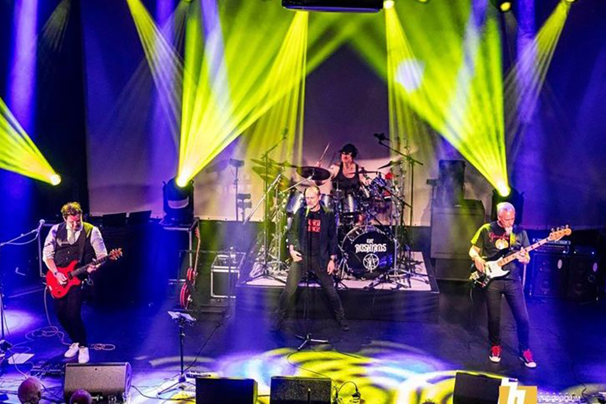 Band speelt op een podium met gele en blauwe lichten