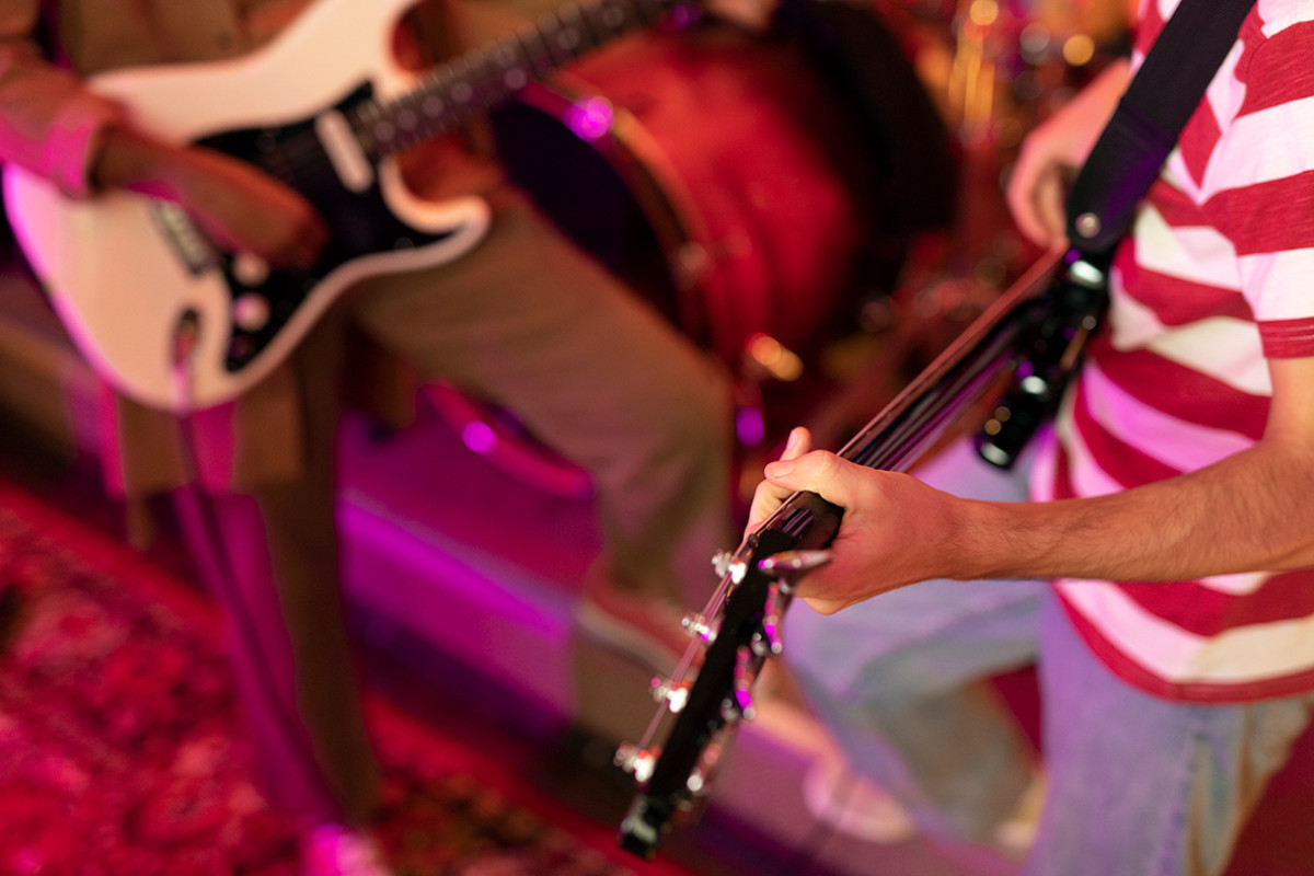 twee paar handen houden een gitaar vast.