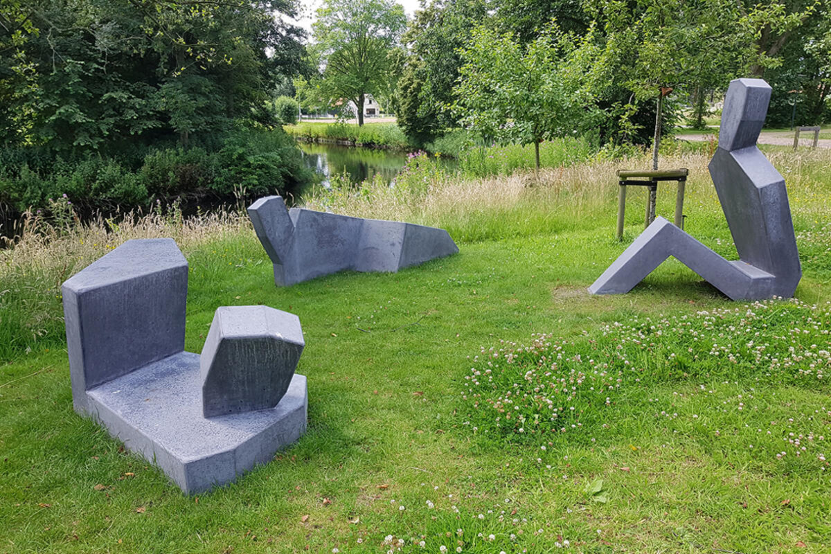 Betonnen beeldhouwwerken waar je op kan zitten in een grasveldveld, omgeven door groen gras.