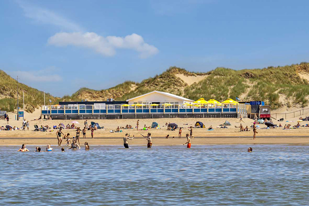 Strandpaviljoen de Vrijheit vanaf de zee gefotografeerd met op de achtergrond de duinen.