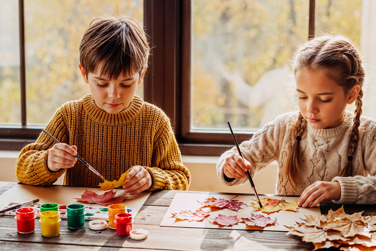 kinderen verfen met herfstbladeren