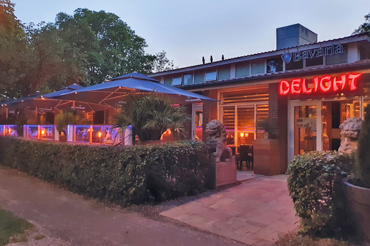 Buitenkant met terras van restaurant Delight met een neonreclame.