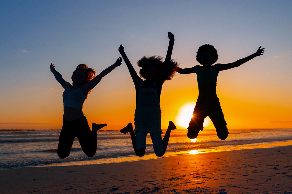 3 personen springen in de lucht voor een zonsondergang
