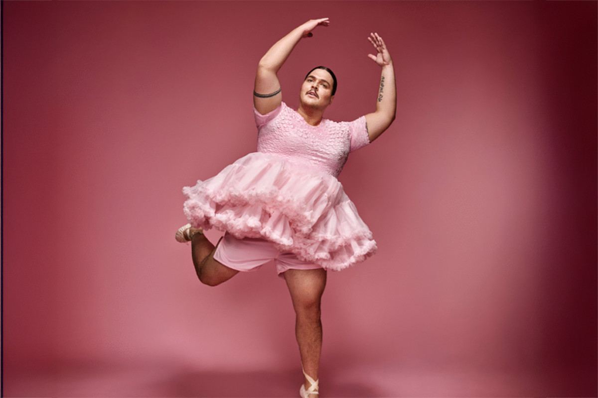 man staat in balletpakje tegen roze achtergrond