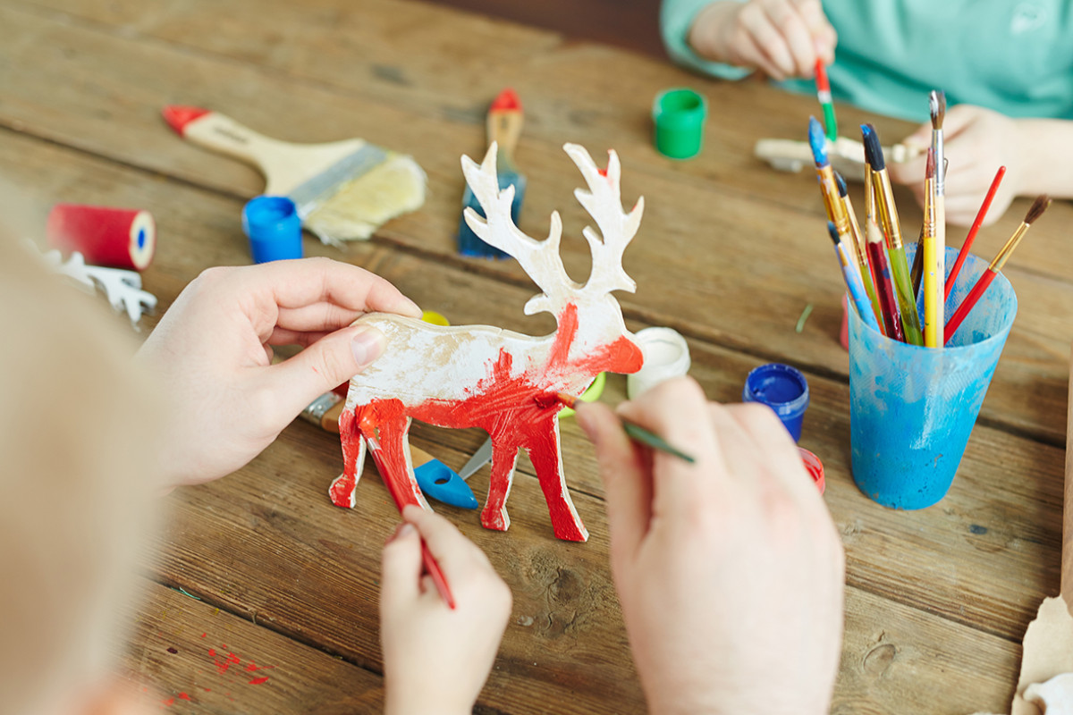 Kinderen schilderen een houten rendier