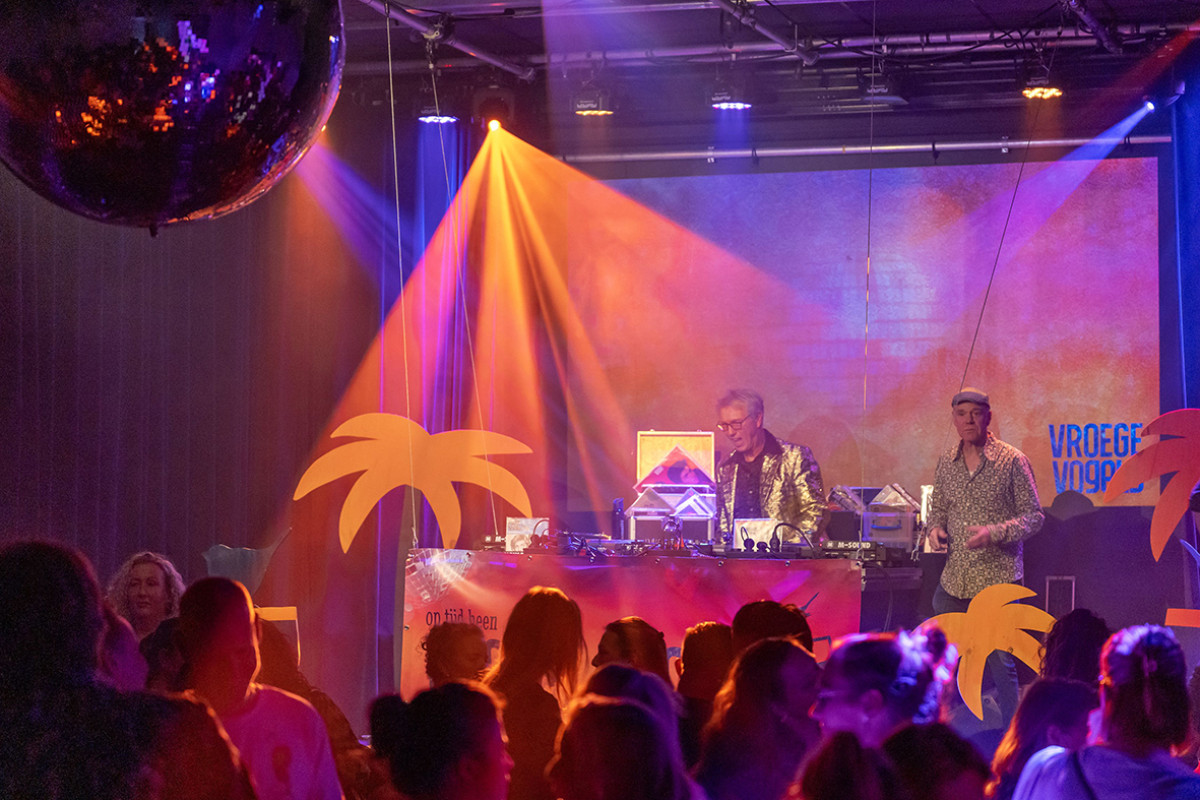 Concertzaal met dansende mensen voor het podium en dj's op het podium