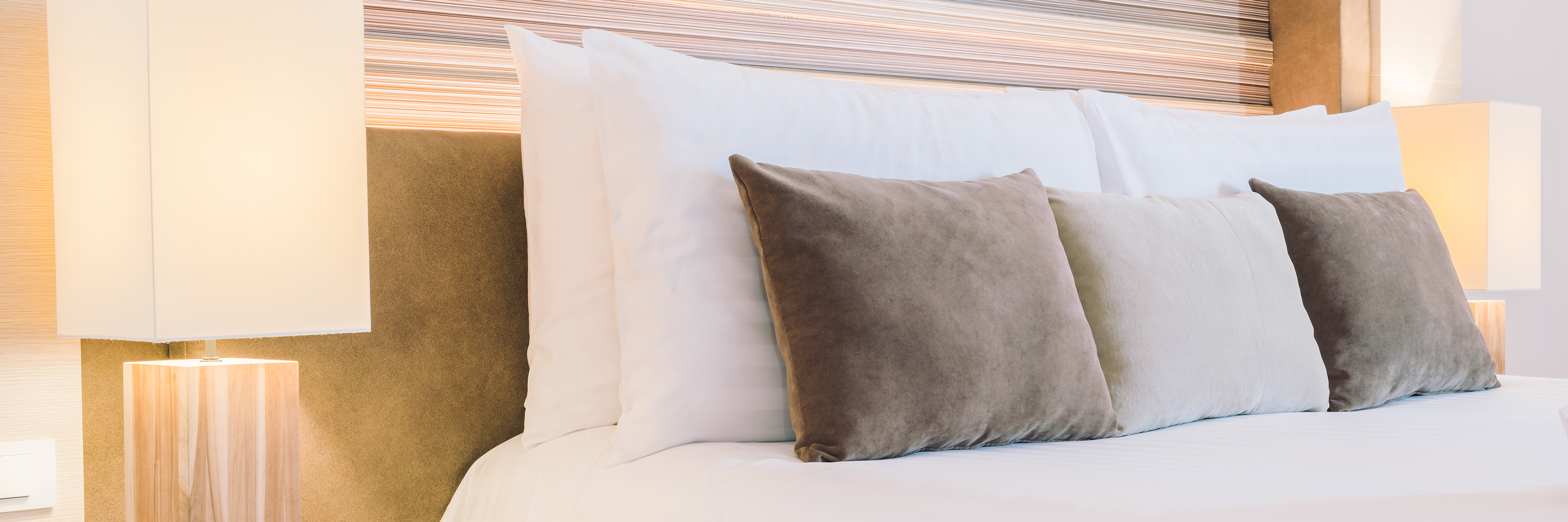 Een bed met kussens en een lamp in een sfeervolle kamer.