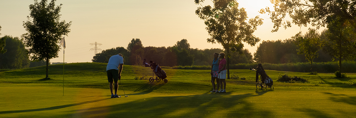 Zonsondergang op de golfbaan, met de laatste zonnestralen die de groene fairways en bunkers verlichten.